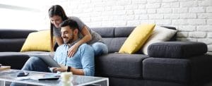 couple-looking-at-computer-on-sofa-we-buy-houses